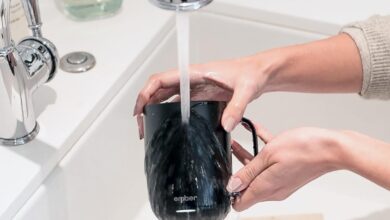 schwarze Ember Smart Mug unter fließendem Wasser im weißen Waschbecken