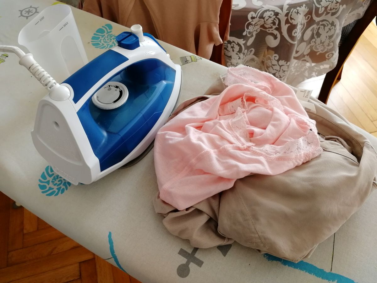 Verschiedene Kleidungsstücke bereit zum Bügeln auf einem Bügelbrett